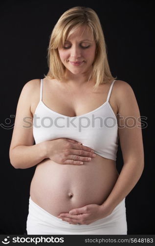 Portrait Of 5 months Pregnant Woman Wearing White On Black Background