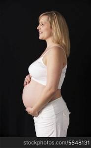 Portrait Of 6 months Pregnant Woman Wearing White On Black Background