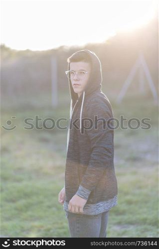 portrait of a attractive teenager standing and looking to you wearing eyeglasses