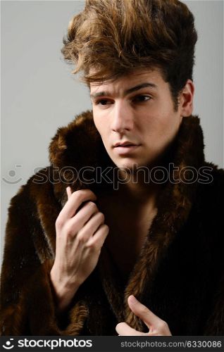 Portrait of a attractive young man wearing fur coat with modern hairstyle