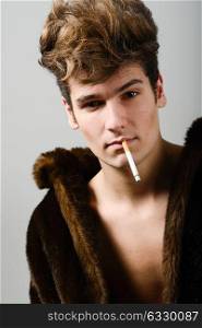 Portrait of a attractive young man wearing fur coat with modern hairstyle