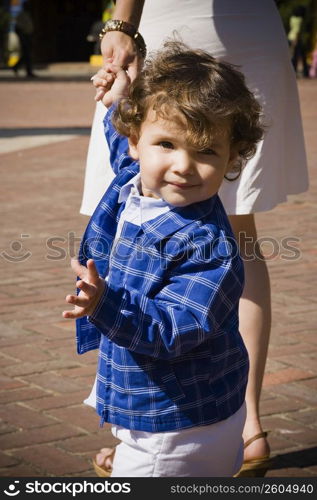 Portrait of a baby boy holding his mother&acute;s hand and walking