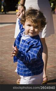 Portrait of a baby boy holding his mother&acute;s hand and walking