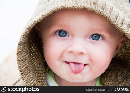 Portrait of a baby in a hood poking his tongue out