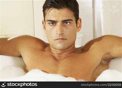 Portrait of a bare chested young man in a bubble bath