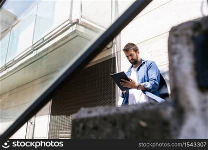 Portrait of a bearded man sitting on steps while using a tablet