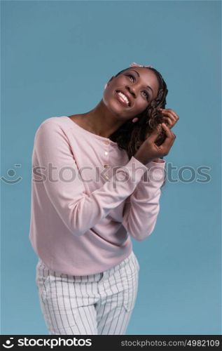 Portrait of a beautiful African young woman thinking and making hair on blue background
