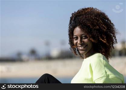 Portrait of a Beautiful afro american woman sitting on shore in a sunny day