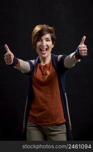 Portrait of a beautiful and happy woman with thumbs up, over a dark background