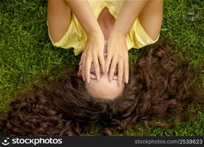 Portrait of a beautiful and happy young woman lying on the grass