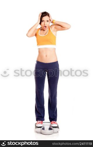 Portrait of a beautiful athletic girl checking her weight, isolated on white