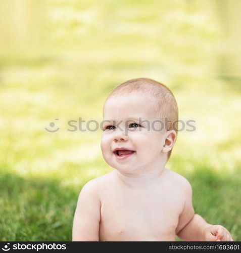 Portrait of a beautiful baby against green nature background outdoors