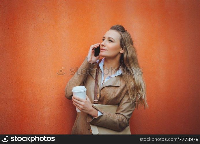Portrait of a Beautiful Blond Student Girl Talking on the Phone and Drinking Coffee. Using Smart Technology for Work and Study. Modern Life.. Serious Student Girl