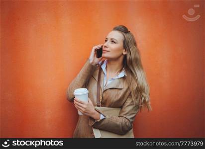 Portrait of a Beautiful Blond Student Girl Talking on the Phone and Drinking Coffee. Using Smart Technology for Work and Study. Modern Life.. Serious Student Girl