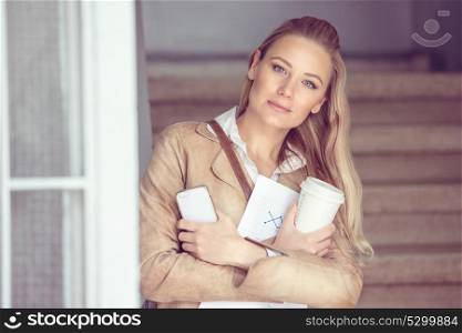 Portrait of a beautiful blond student girl with a coffee and phone, smart intelligent youth, white collar worker, back to school concept