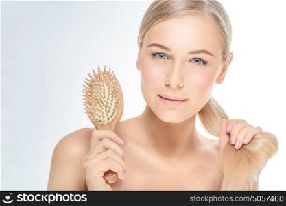 Portrait of a beautiful blond woman combing her perfect straight hair over clear background, fashion model with natural makeup, beauty salon