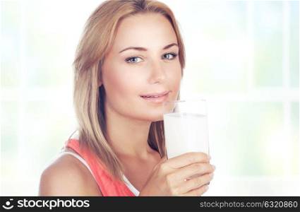 Portrait of a beautiful blond woman drinking milk at home, organic beverage for the breakfast, healthy nutrition concept
