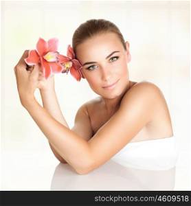 Portrait of a beautiful blond woman with orchid flowers in the head and hand spending day at spa salon, beauty and health treatment