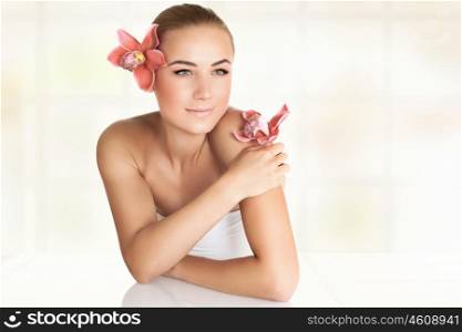 Portrait of a beautiful blond woman with orchid flowers, spending day at spa salon, relaxation during medical beauty treatments, skin care