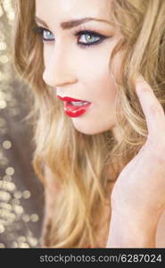 Portrait of a beautiful blond young woman female model with green eyes smiling and blond hair wearing red lipstick in a nightclub party atmosphere