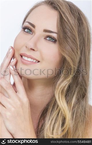 Portrait of a beautiful blond young woman with green eyes smiling and touching her face with her hands