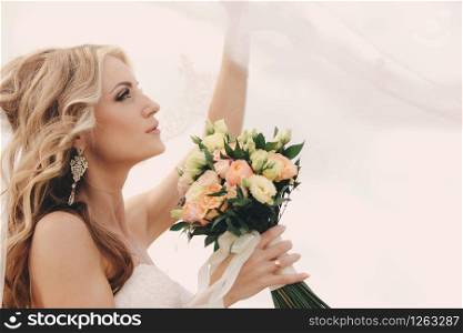 portrait of a beautiful blonde bride with a bouquet of flowers ith wedding makeup and hairstyle. luxury bride with veil over her face. Closeup portrait of young gorgeous bride. Wedding. copy space.. portrait of a beautiful blonde bride with a bouquet of flowers ith wedding makeup and hairstyle. luxury bride with veil over her face. Closeup portrait of young gorgeous bride. Wedding. copy space