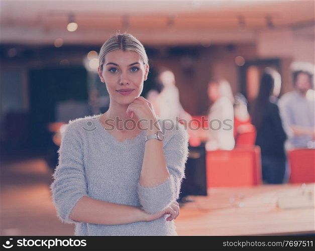 Portrait of a beautiful blonde businesswoman as a team leader looking at camera and smiling. Multiethnic colleagues in background Diverse team in modern open space startup office. High quality photo. Beautiful blonde businesswoman looking at camera and smiling coworkers diverse team in modern open space office in background