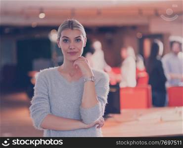 Portrait of a beautiful blonde businesswoman as a team leader looking at camera and smiling. Multiethnic colleagues in background Diverse team in modern open space startup office. High quality photo. Beautiful blonde businesswoman looking at camera and smiling coworkers diverse team in modern open space office in background