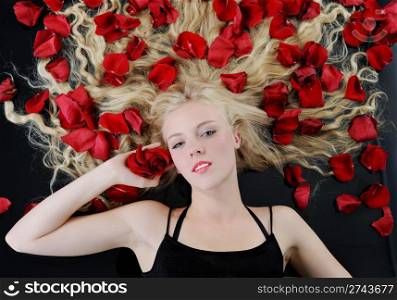 Portrait of a beautiful blonde in red rose petals