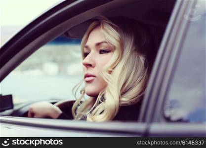 portrait of a beautiful blonde woman driving a sports car