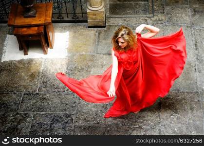 Portrait of a beautiful blonde woman, wearing a red dress, jumping