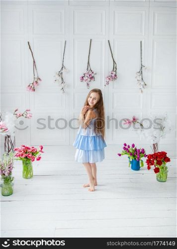 Portrait of a beautiful blue-eyed girl, a little girl among spring flowers in a bright room. Spring break, Mother&rsquo;s Day, Women&rsquo;s Day, Easter.. Portrait of a beautiful blue-eyed girl, a little girl among spring flowers in a bright room.