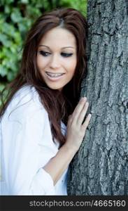 Portrait of a beautiful brunette girl next to a tree
