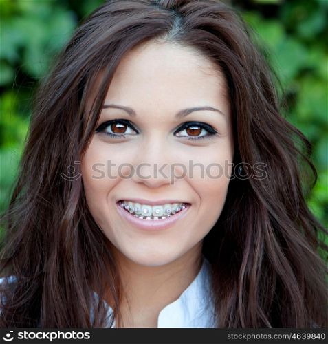 Portrait of a beautiful brunette girl with brackets outdoors in the park