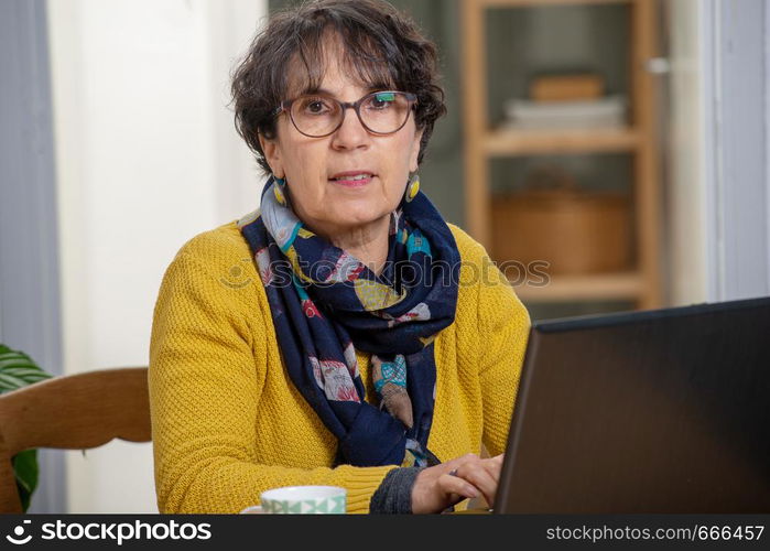 portrait of a beautiful brunette mature woman with laptop at home