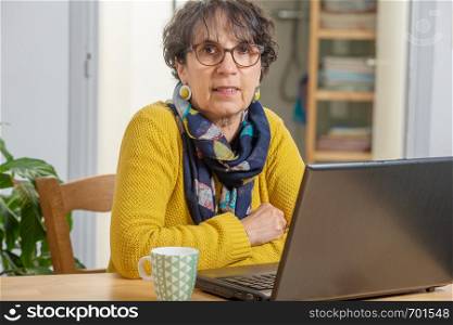 portrait of a beautiful brunette mature woman with laptop at home