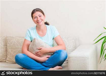 portrait of a beautiful brunette with a pillow on a sofa