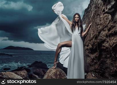 Portrait of a beautiful brunette woman posing on the rock