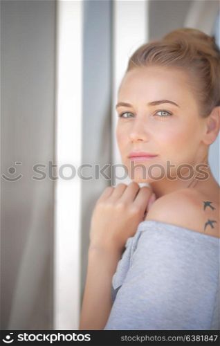 Portrait of a beautiful calm woman at home, casual gorgeous female standing near window, natural authentic beauty