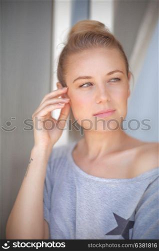 Portrait of a beautiful calm woman at home, standing near window and thinking, natural authentic beauty