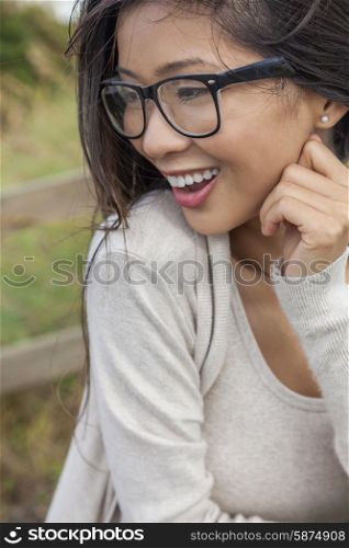 Portrait of a beautiful Chinese Asian girl or young woman outside wearing glasses happy and laughing