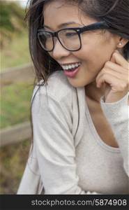 Portrait of a beautiful Chinese Asian girl or young woman outside wearing glasses happy and laughing
