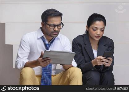 Portrait of a beautiful corporate couple doing office work using digital tablet and smartphone