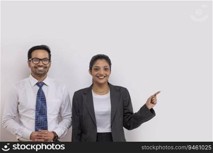Portrait of a beautiful corporate couple looking at camera with smile and pointing elsewhere
