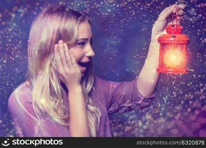 Portrait of a beautiful excited woman surprised looking on a glowing light in lantern, true miracle in Christmas eve, happy magical night