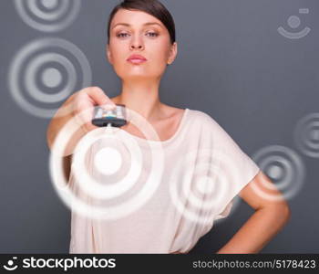 Portrait of a beautiful fashionable elegant woman with remote control choosing channels. Copyspace