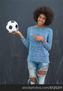 portrait of a beautiful friendly African American woman with a curly afro hairstyle and lovely smile holding a soccer ball isolated on a gray background