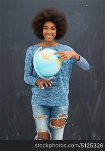 portrait of a beautiful friendly African American woman with a curly afro hairstyle and lovely smile holding Globe of the world isolated on a gray background