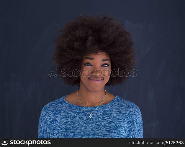 portrait of a beautiful friendly African American woman with a curly afro hairstyle and lovely smile sitting isolated on a gray background