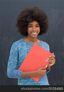 portrait of a beautiful friendly African American woman with a curly afro hairstyle and red folder isolated on a gray background